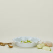 Porcelain pie dish in white with measuring spoons, dough, and apple slices