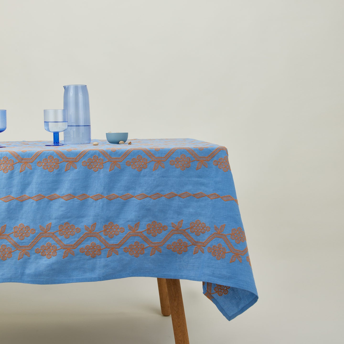 Napa tablecloth in blue on table with pitcher, glasses, and bowl with nuts.