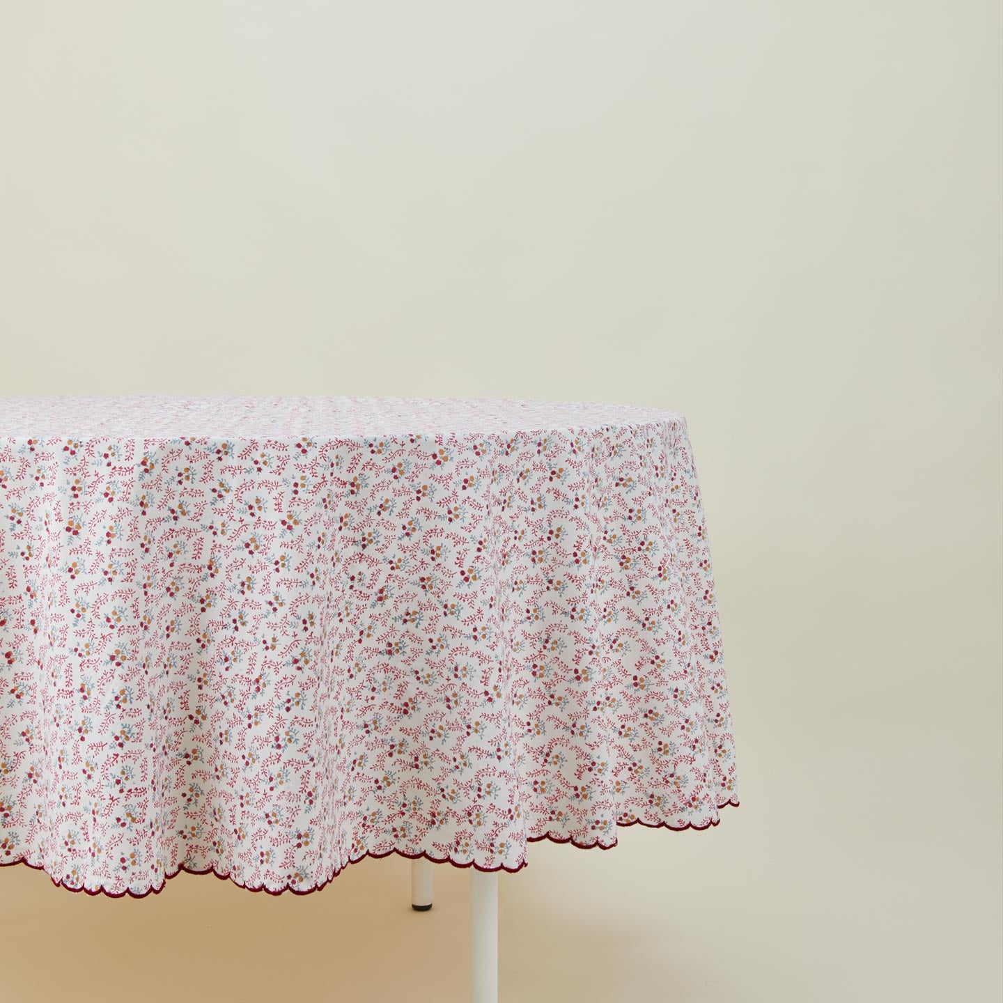 Round little flowers tablecloth in maroon on table.