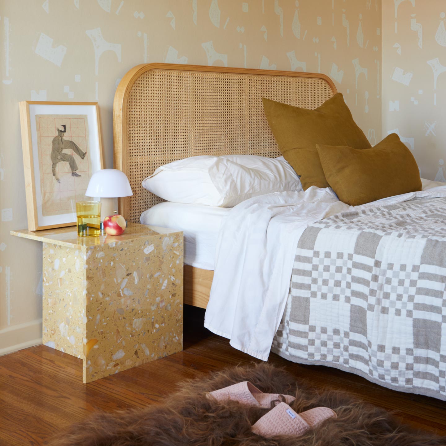 Bedroom with a bed featuring a wicker headboard, nightstand, and decorative items.