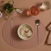 Dinner setting with a bowl of dumplings, pink chopsticks, spoon, and glasses on a pink placemat.