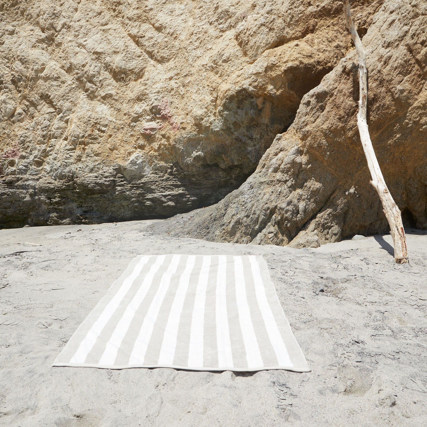 A striped ivory and flax terry towel at the beach.
