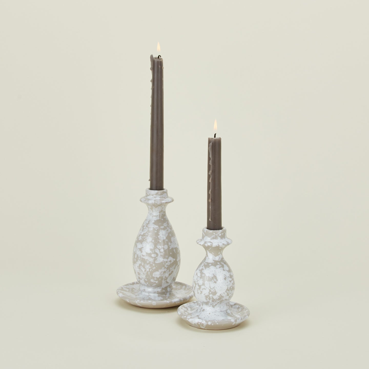Large and small splatterware candlesticks in white and grey with candles