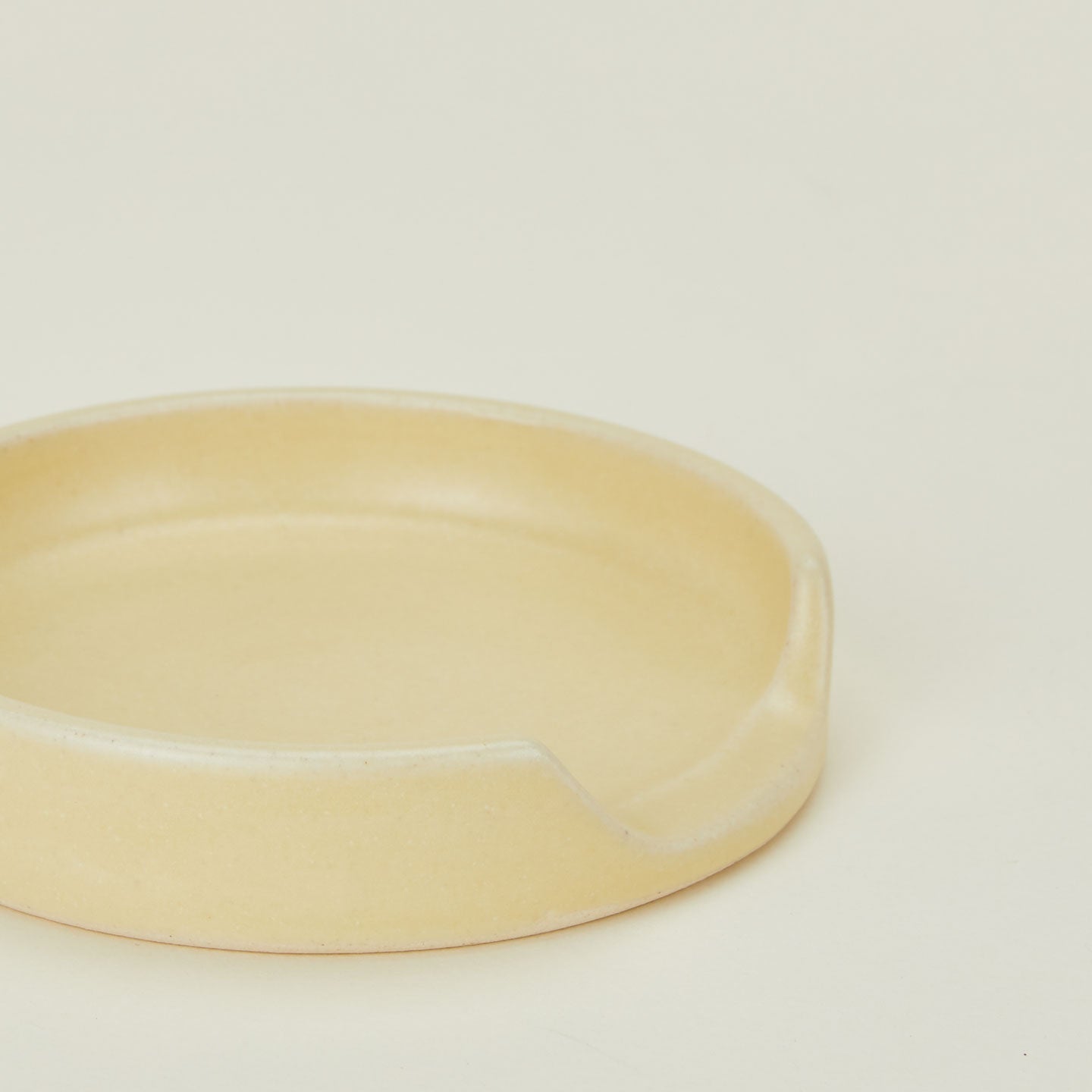 A close up of a butter stoneware spoon rest.
