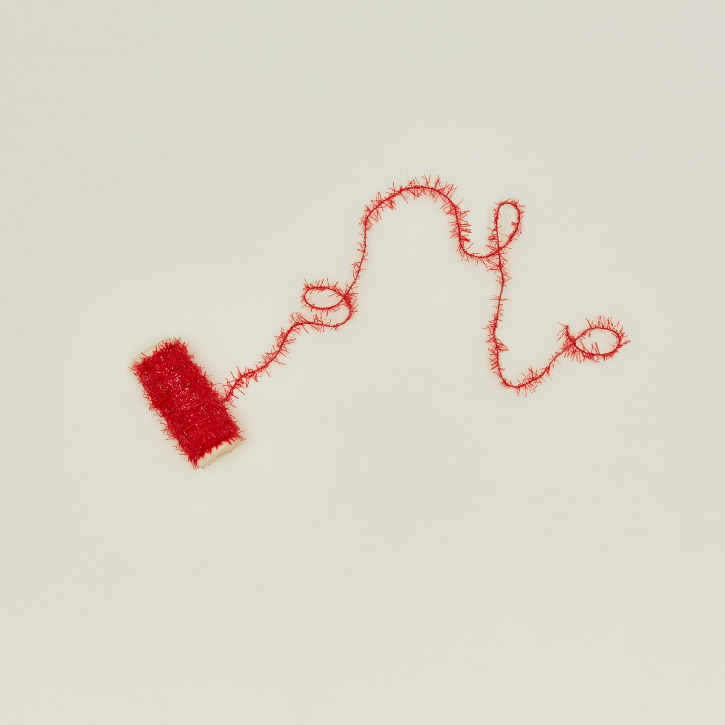 Tinsel ribbon in red unspooling on neutral background